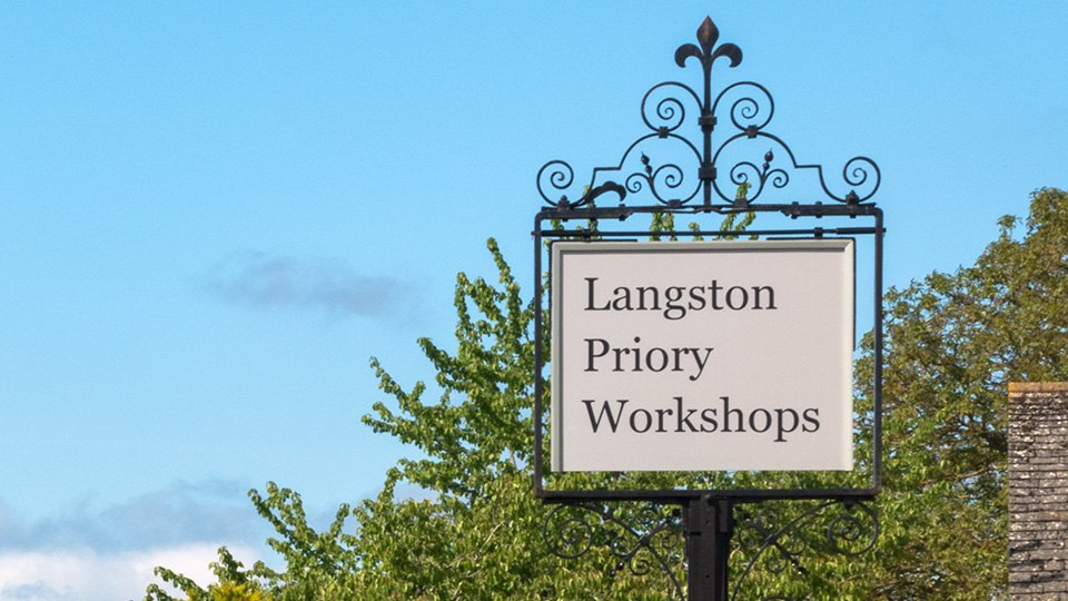 Langston Priory Workshops sign against a blue sky