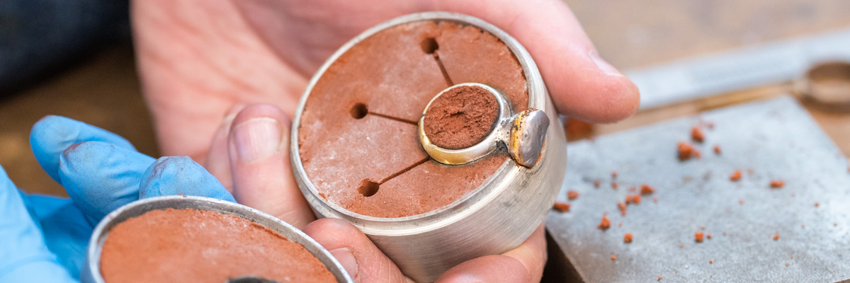 A sand cast a silver ring in a casting flask full of sand