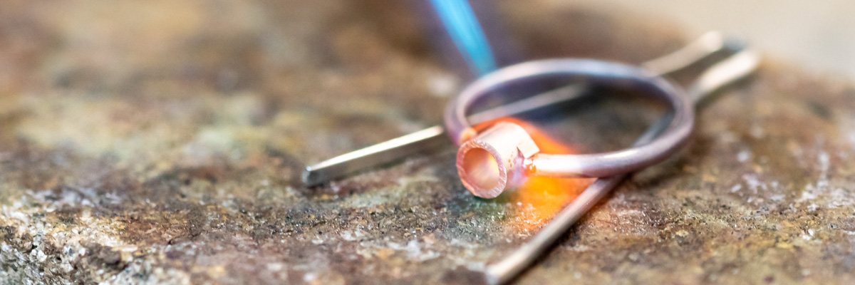 A silver ring being soldered together using a jewellery torch