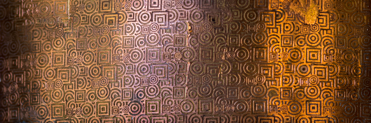 A copper sheet with geometrically patterned surface texture made of squares and circles