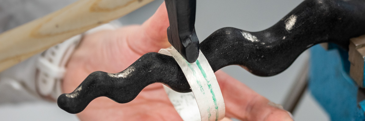 A silver bangle being hammered on an anticlastic raising stake in a jewellery workshop