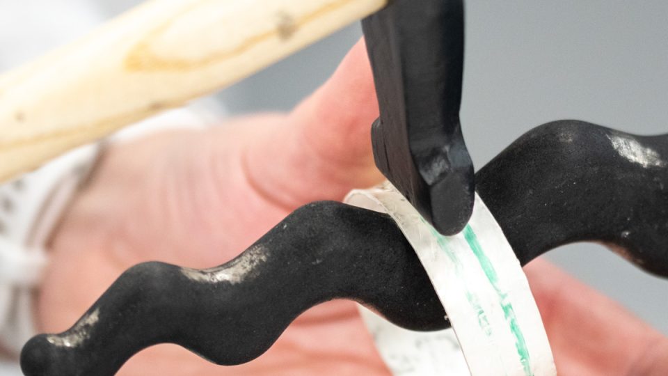 Silver bangle being hammered on a anticlastic raising stake