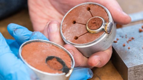 Sand cast silver ring in a flask full of sand being opened